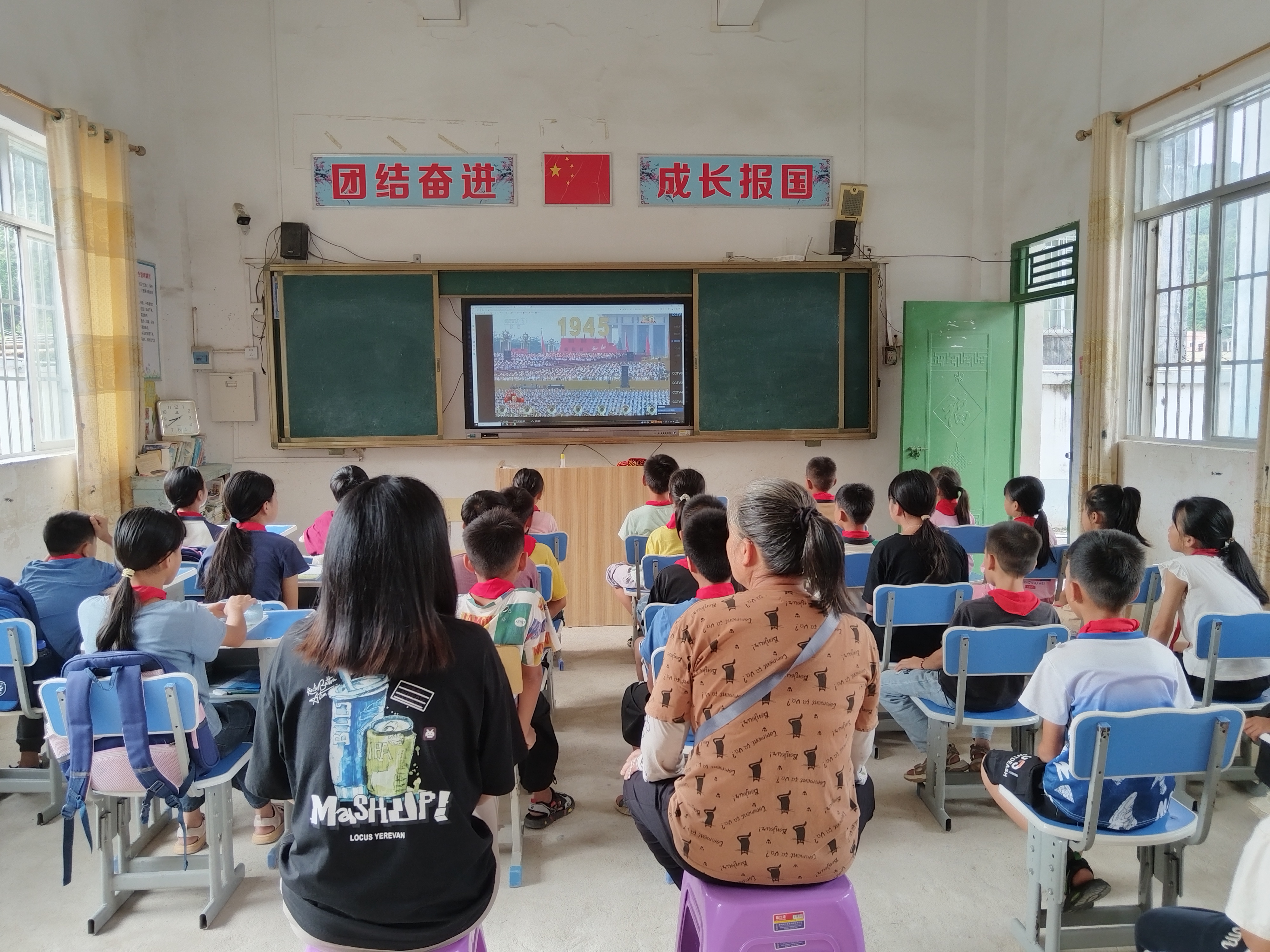 欽北區(qū)板城鎮(zhèn)高龍小學(xué)家長和學(xué)生一起觀看閱兵儀式。.jpg